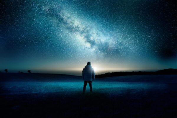 An alone man is standing and looking toward night view of the sky